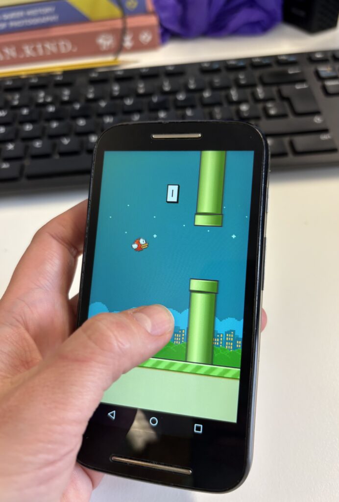 Someone holding a phone in one hand, demonstrating how Flappy Bird was designed to be played.